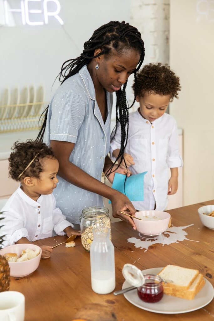 Caring mother helps kids clean spilled breakfast on a sunny morning.